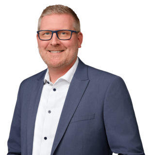 Mann im Anzug lächelt in einer Porträtaufnahme